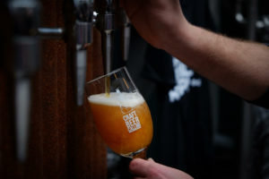 Image shows craft beer being poured from a tap into a glass that reads Craft Beer Calling